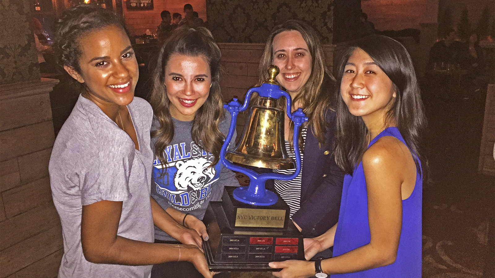 Bruins hold up the NYC Victory Bell flag football trophy